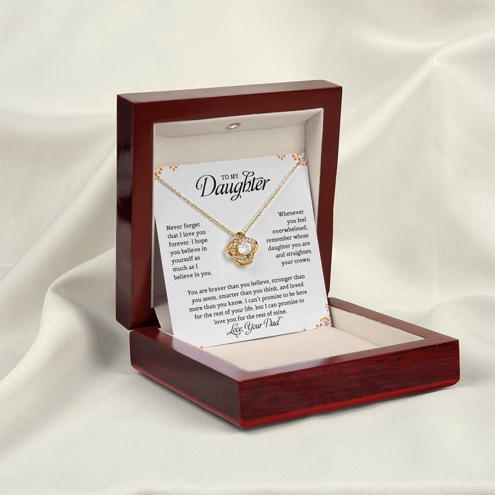 A necklace with a love knot pendant in a mahogany gift box, accompanied by a card with a message to the daughter from dad expressing love and belief in her.